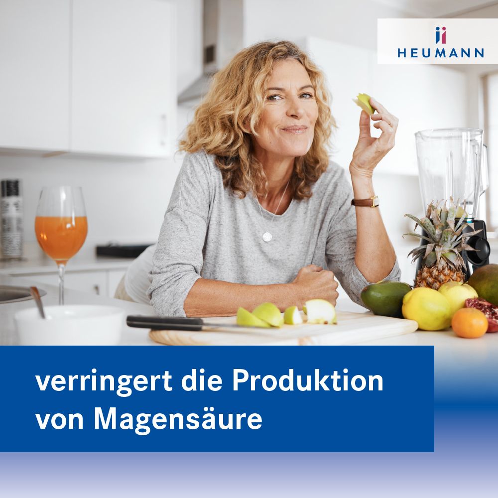 Frau schneidet Obst. Im Hintergrund: Mixer und Früchte. Text: verringert die Produktion von Magensäure. Logo HEUMANN.