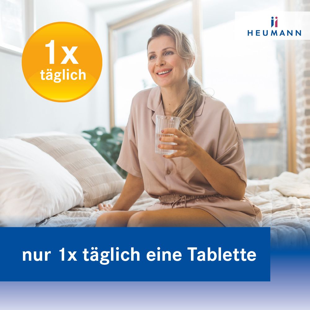 Frau sitzt auf dem Bett, hält ein Glas Wasser. Text: nur 1x täglich eine Tablette. Logo HEUMANN.