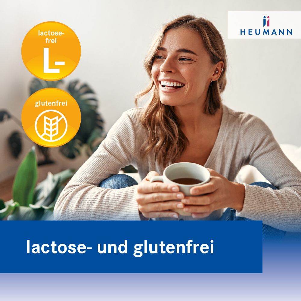 Frau sitzt auf dem Bett, hält eine Tasse. Text: lactose- und glutenfrei. Logos: lactosefrei, glutenfrei. Logo HEUMANN.