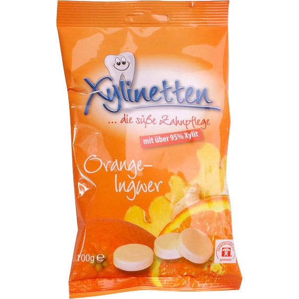 Verpackung von Xylinetten Bonbons Orange-Ingwer. Orangefarbene Tüte mit Produktnamen, Zahn-Illustration und Bonbon-Abbildung.