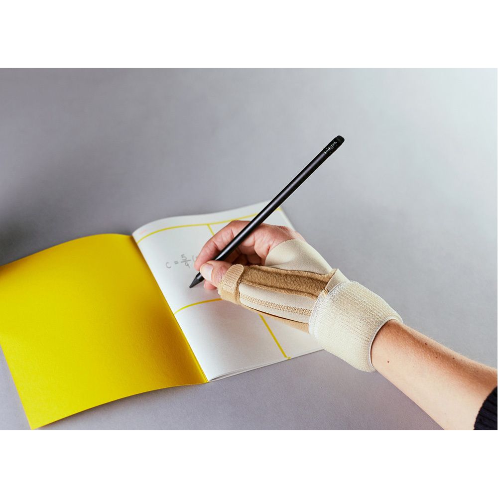 Person schreibt mit einem Stift, trägt eine FUTURO Daumen-Schiene. Gelbes Notizbuch.