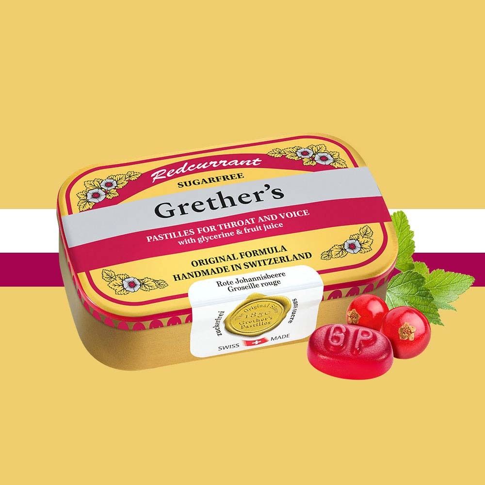 Goldene Dose mit roter Aufschrift Redcurrant Sugarfree Grether's Pastilles. Rote Pastille, Johannisbeeren und Blattwerk daneben.