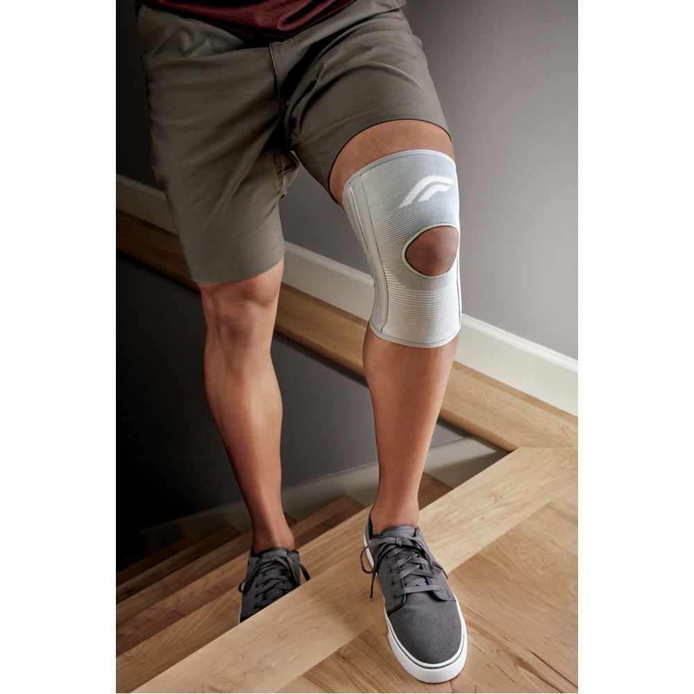 Person trägt FUTURO® Knie-Bandage beim Treppensteigen. Graue Bandage, graue Schuhe, braune Treppe.