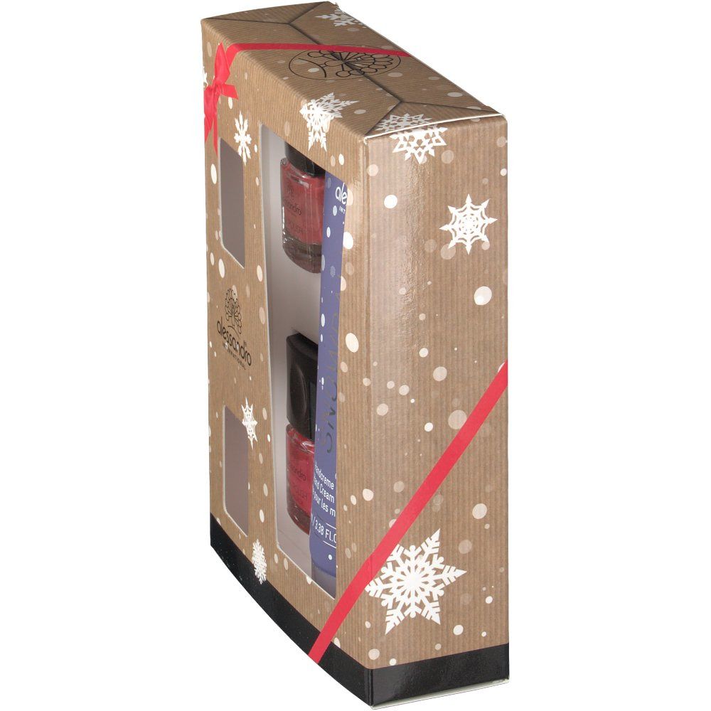 Geschenkset-Verpackung, seitliche Ansicht. Handcreme-Tube und Nagellackflaschen durch Fenster sichtbar. Verpackung mit Schneeflocken und roter Schleife.