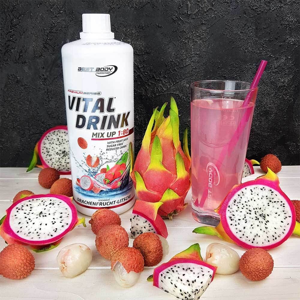 Verre avec boisson rose, paille, fruits. Bouteille Vital Drink, fruits: fruit du dragon, litchi. Inscription: Drachenfrucht-Litschi.