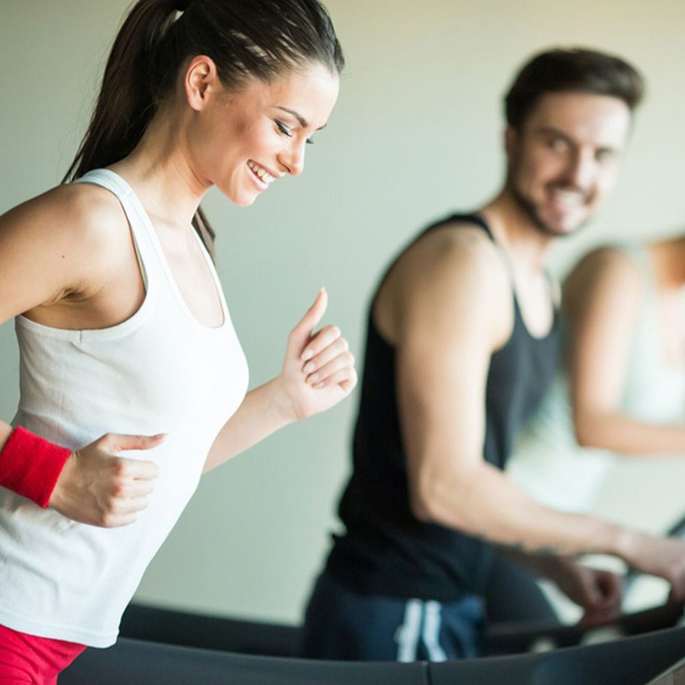 Frau und Mann auf Laufbändern im Fitnessstudio. Frau lächelt. Sportliche Aktivität.