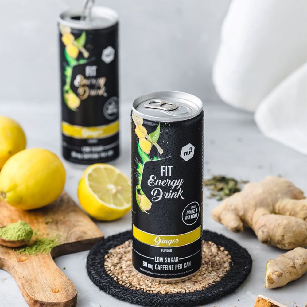 Zwei Dosen "nu3 Fit Energy Drink" mit Ingwer, Zitronen und Matcha-Pulver auf einer Oberfläche.