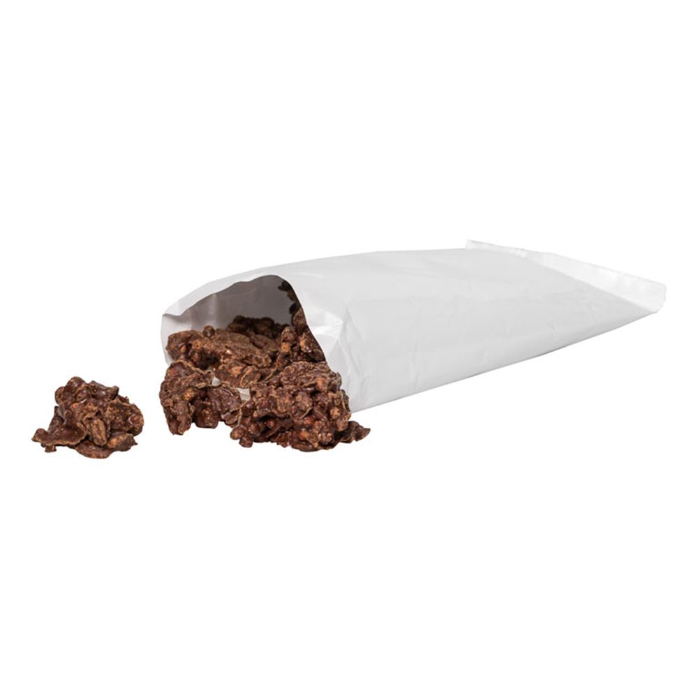 Geöffnete weiße Tüte mit Protein Crossies. Einige Crossies liegen daneben.