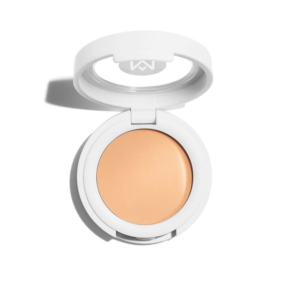 Weißer Concealer-Behälter, geöffnet. Helle, beige Creme sichtbar. Logo 'M' im Deckel.