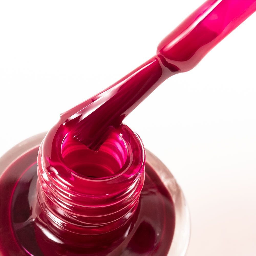 Nahaufnahme einer Nagellackflasche. Der Pinsel ist in den Nagellack getaucht. Der Nagellack ist dunkelrot.
