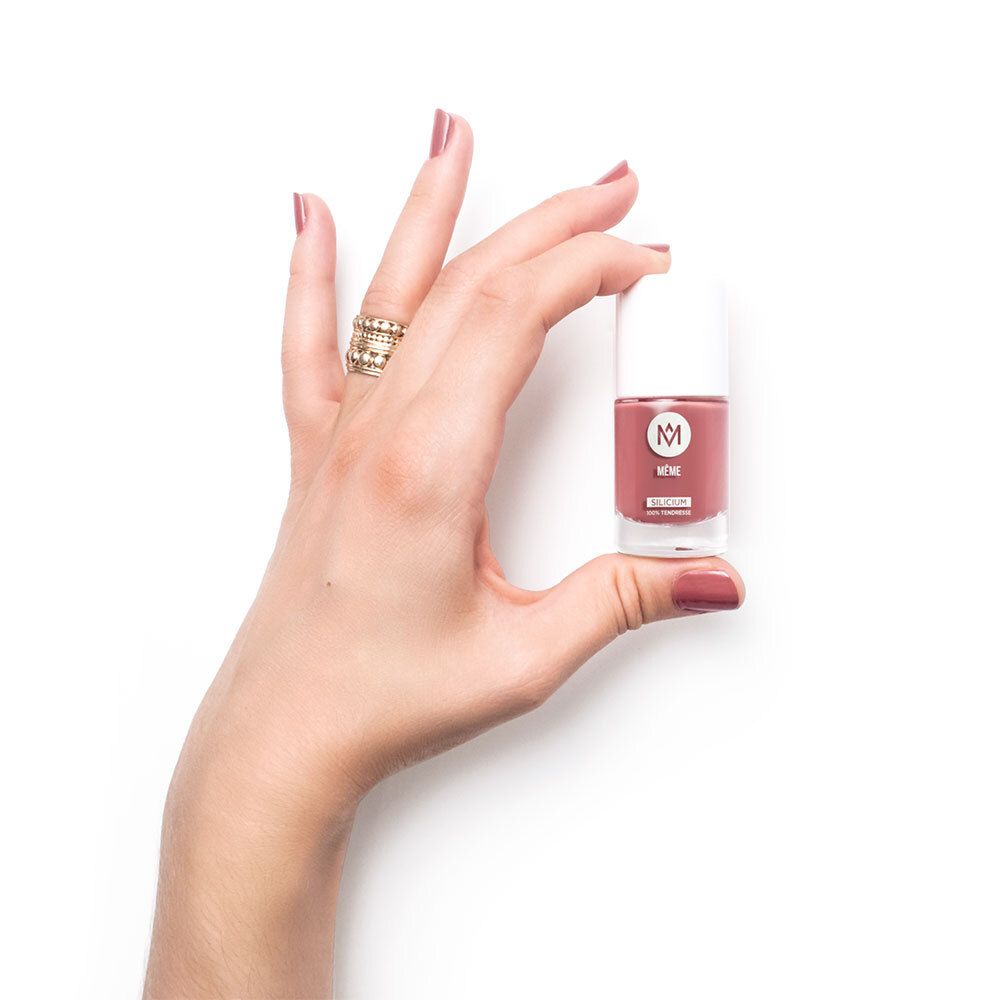 Hand hält eine Nagellackflasche. Der Nagellack ist rosa. Auf der Flasche steht "MÉME".