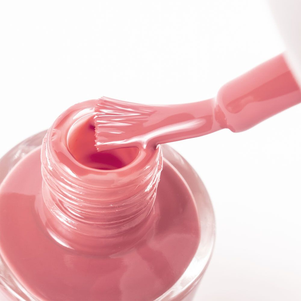 Nahaufnahme einer Nagellackbürste in einer Nagellackflasche. Der Nagellack ist rosa.