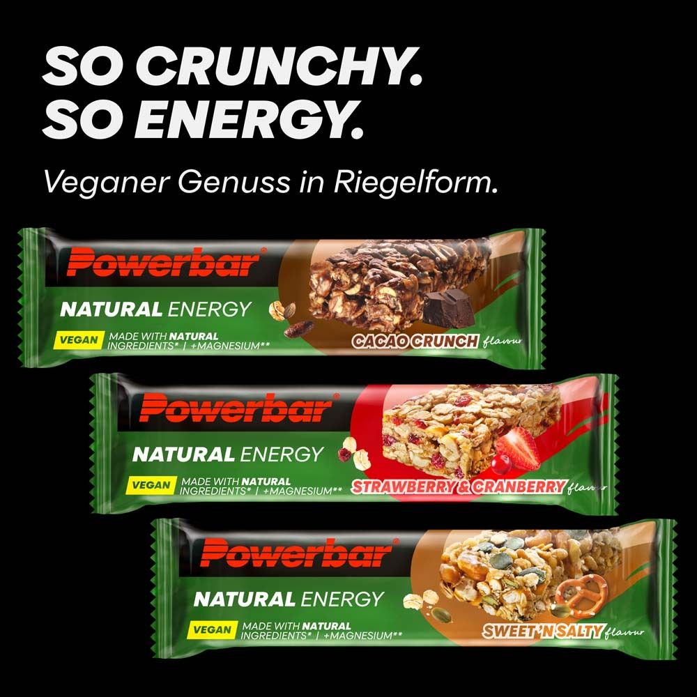 Drei PowerBar Natural Energy Riegel. Erdbeer-Cranberry, Cacao Crunch, Sweet 'n Salty. Schwarzer Hintergrund. Vegan.