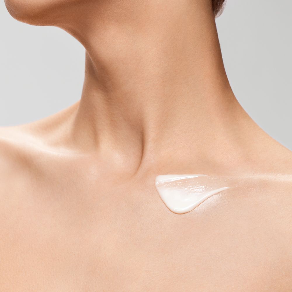 Eine weiße Creme ist auf dem Dekolleté aufgetragen.