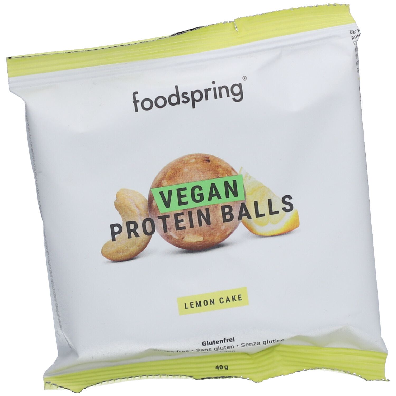 Verpackung von foodspring Vegan Proteinballs Lemon Cake. Weiße Tüte mit Produktabbildung und Schriftzug. Grün-gelbe Akzente.