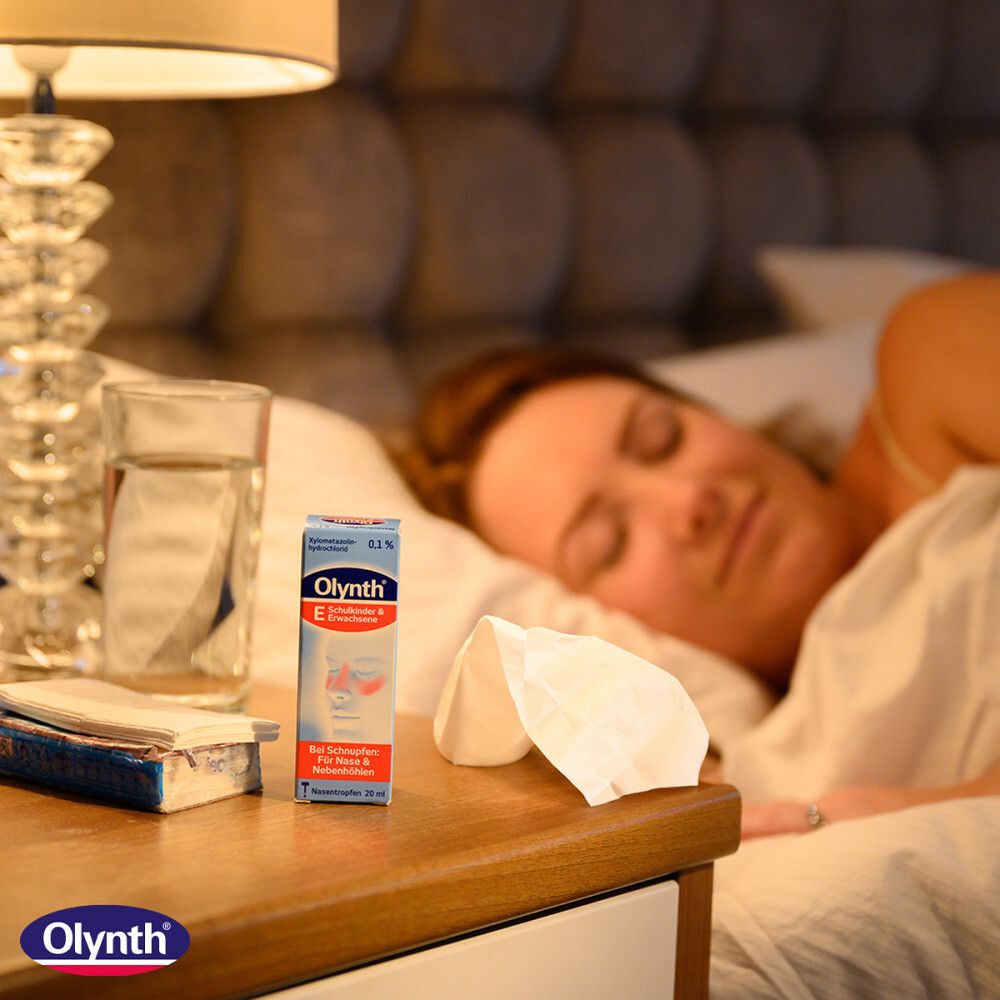 Schlafzimmer-Szene. Auf dem Nachttisch: Olynth 0,1% Packung, Taschentücher, Glas Wasser. Frau schläft im Bett.