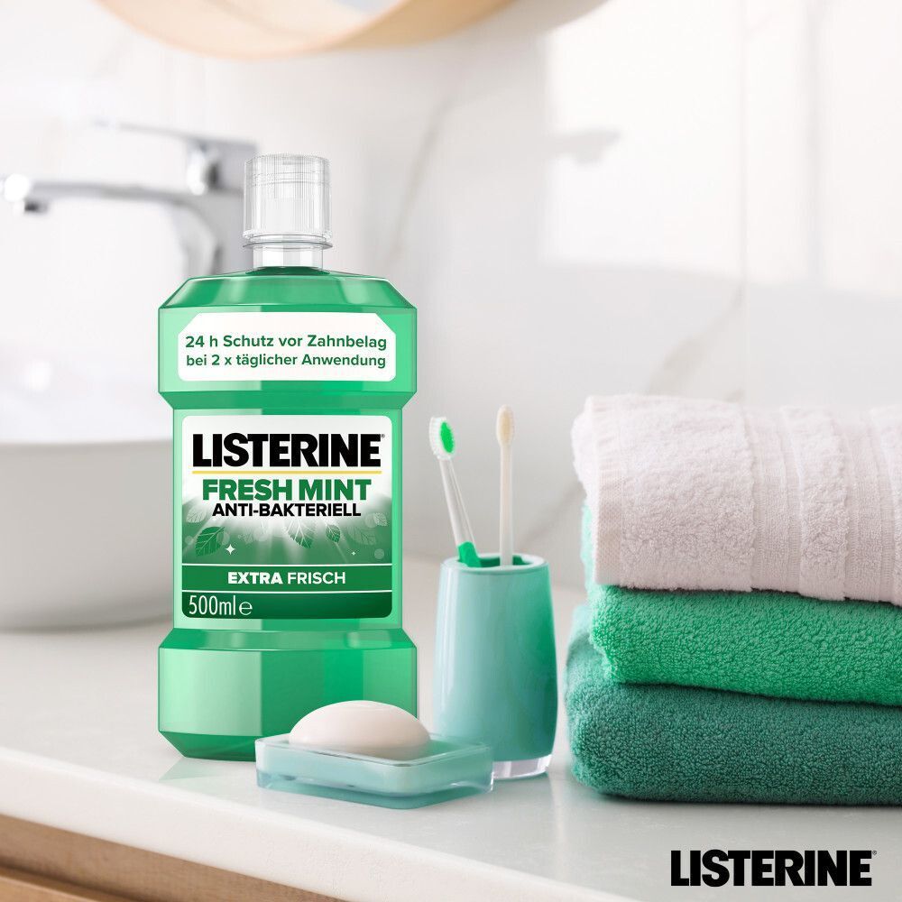 LISTERINE® Fresh Mint Mundspülung (500ml) im Badezimmer neben Handtüchern und Zahnbürsten.