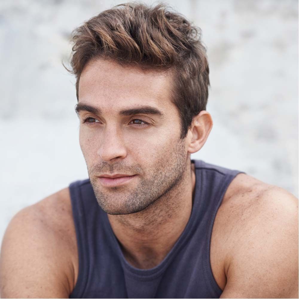 Porträt eines Mannes mit braunen Haaren und blauem Tanktop. Blick zur Seite.