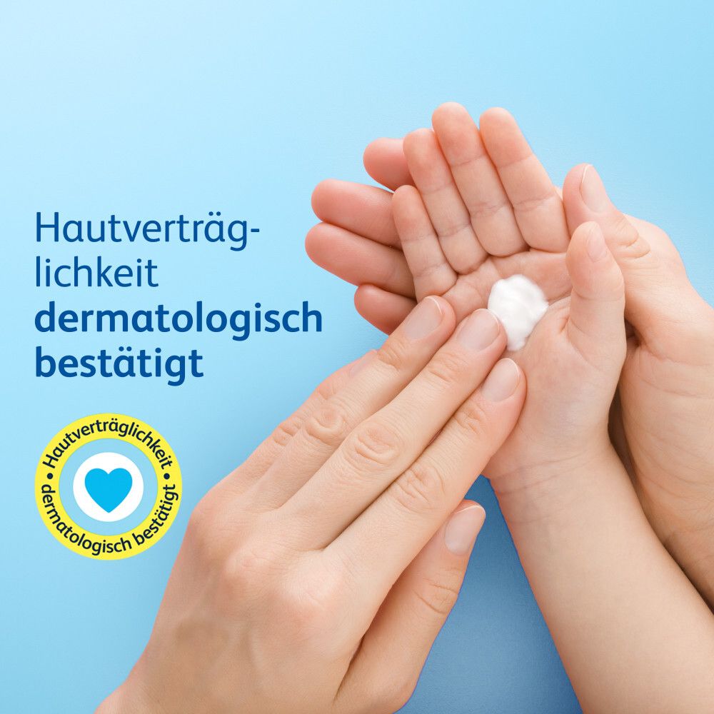 Hände halten Babyhand mit Creme. Text: Hautverträglichkeit dermatologisch bestätigt. Herz-Symbol.