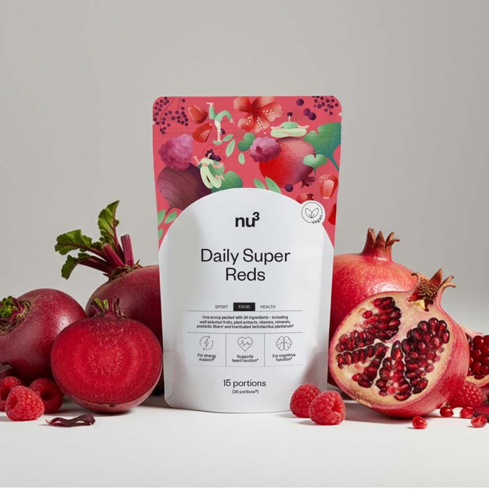 Produktverpackung „nu3 Daily Super Reds“ mit roten Früchten. Rote Bete, Himbeeren und Granatäpfel umgeben das Produkt.