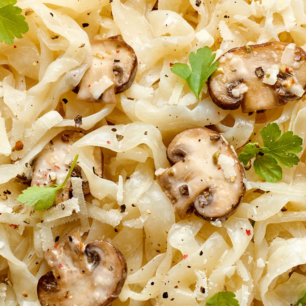 Nahaufnahme von Konjak-Tagliatelle mit Pilzen und Petersilie, gewürzt mit Pfeffer.