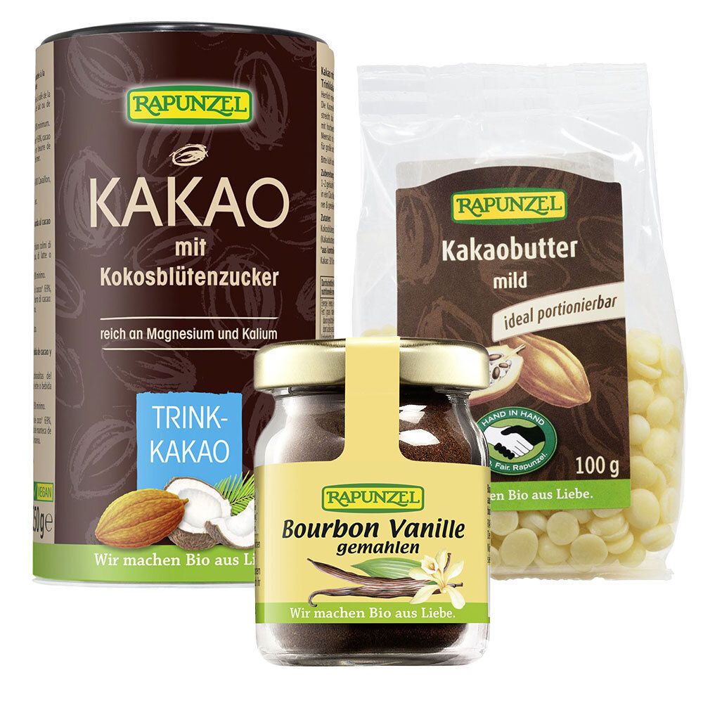 Drei Produkte: Kakaopulver, Kakaobutter und Bourbon Vanille. Kakaopulver in Dose, Kakaobutter in Beutel, Vanille in Glas. Alle mit Logo.