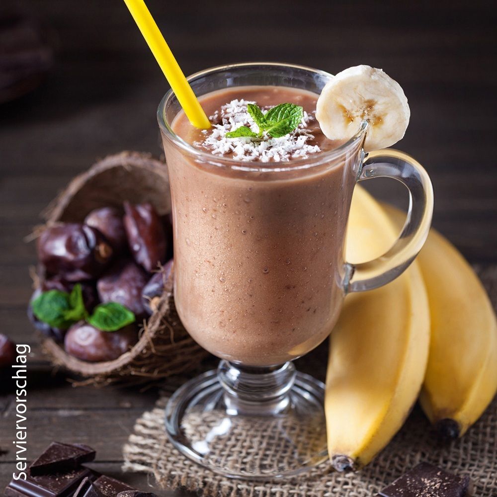 Schokoladen-Bananen-Shake in einem Glas mit Kokosnuss, Datteln, Schokolade und Bananen.