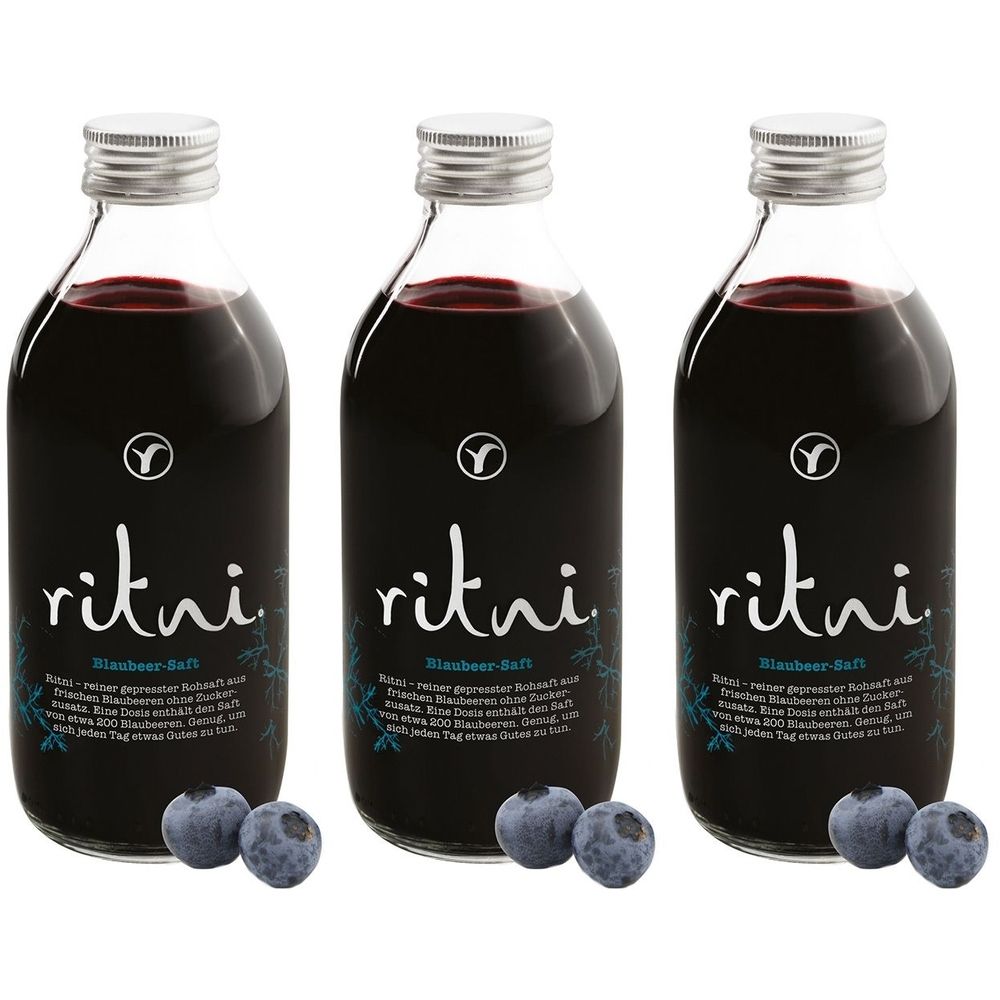 Drei Glasflaschen mit blauem Saft, silbernen Deckeln und Etiketten. Blaubeeren liegen davor. Aufschrift: ritni Blaubeer-Saft.