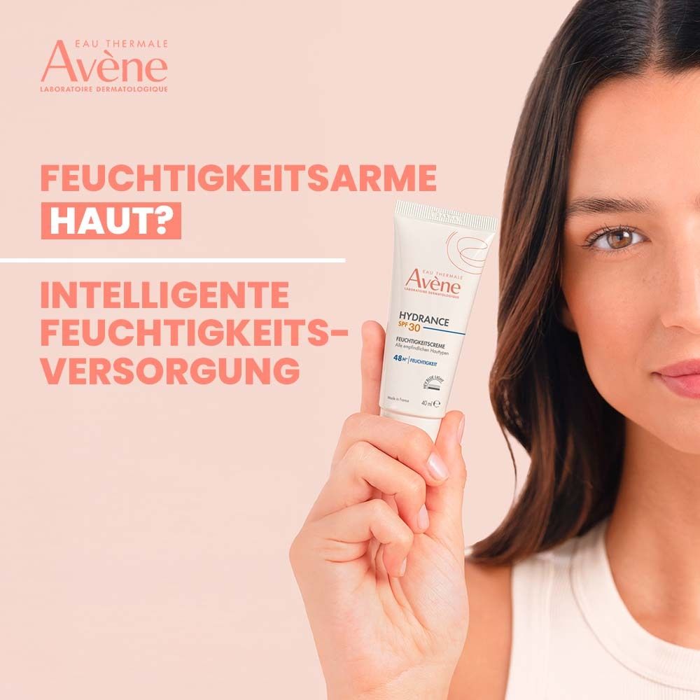 Frau hält Avène Hydrance Feuchtigkeitscreme SPF 30. Text: Feuchtigkeitsarme Haut? Intelligente Feuchtigkeitsversorgung. Tube weiß mit roter Schrift.