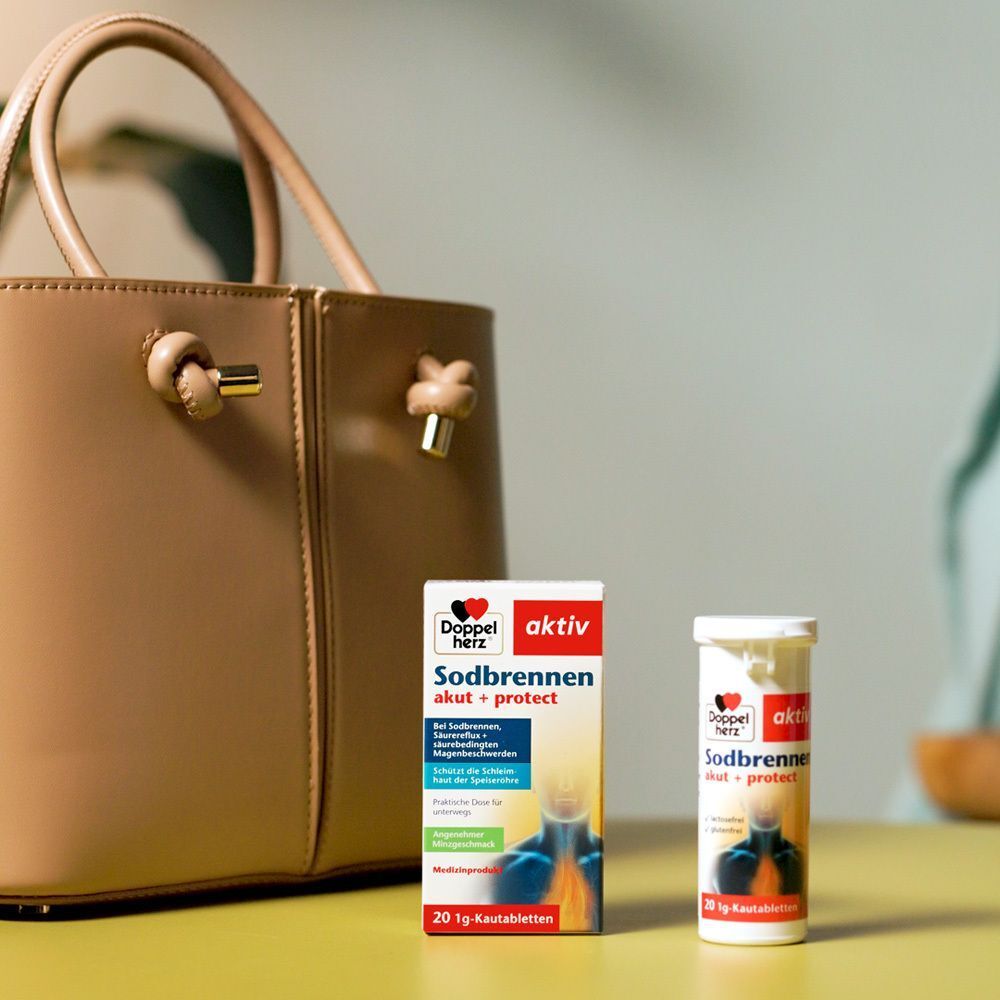 Packung und Dose Doppelherz Sodbrennen akut + protect Kautabletten neben einer Handtasche.