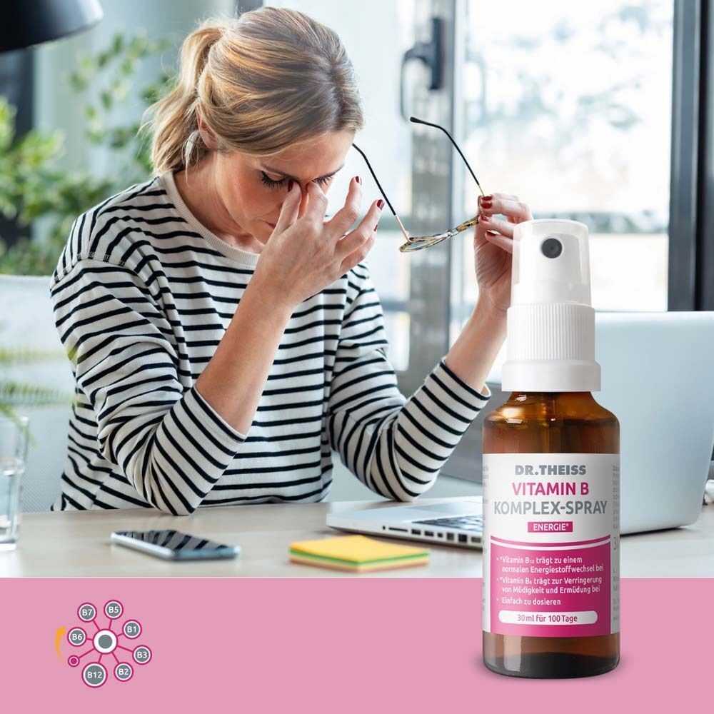 Eine Frau reibt sich die Augen am Schreibtisch, daneben steht eine Flasche DR. THEISS Vitamin B Komplex Spray.