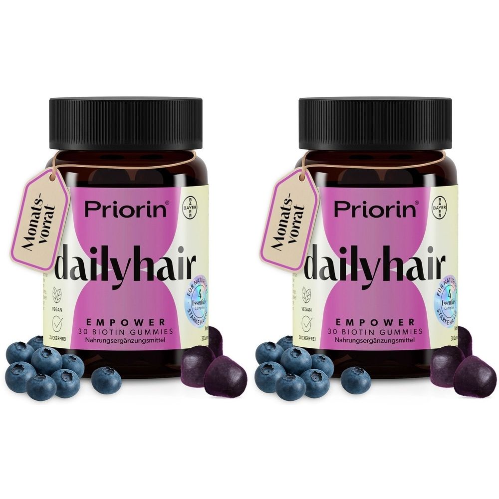 Zwei braune Flaschen mit schwarzen Deckeln. Auf jeder Flasche befindet sich ein Etikett mit der Aufschrift "Priorin dailyhair EMPOWER". Blaubeeren und Gummibärchen.