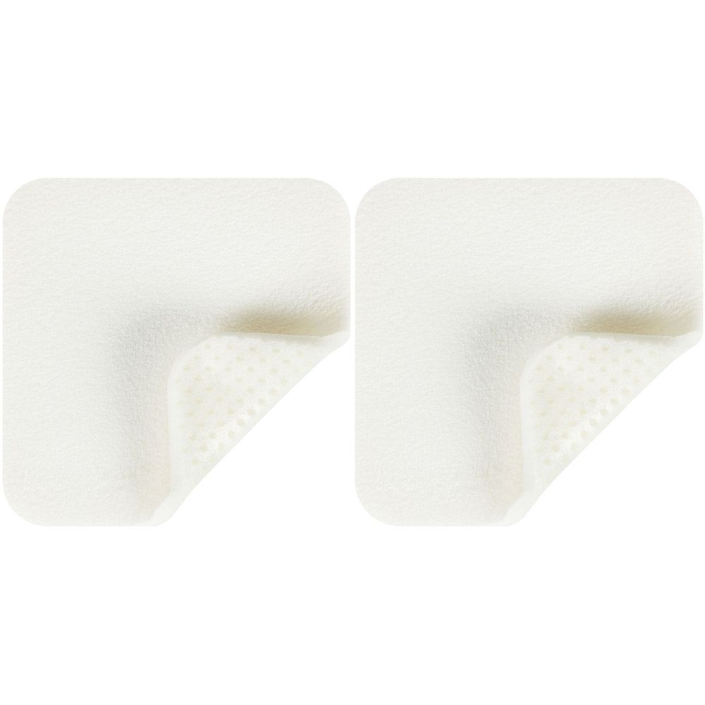 Zwei quadratische, weiße Schaumstoffverbände mit abgerundeten Ecken. Die untere Ecke ist umgeklappt und zeigt eine perforierte Oberfläche.