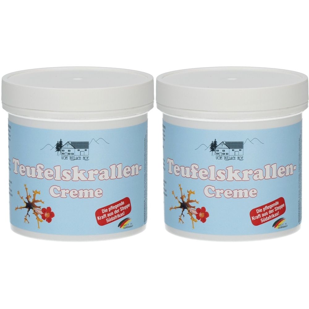 Zwei Tiegel mit weißem Deckel und hellblauem Etikett. Aufschrift: Teufelskrallen-Creme. Logo: Haus mit Bergen. Rotes Etikett mit Text und Deutschland-Flagge.