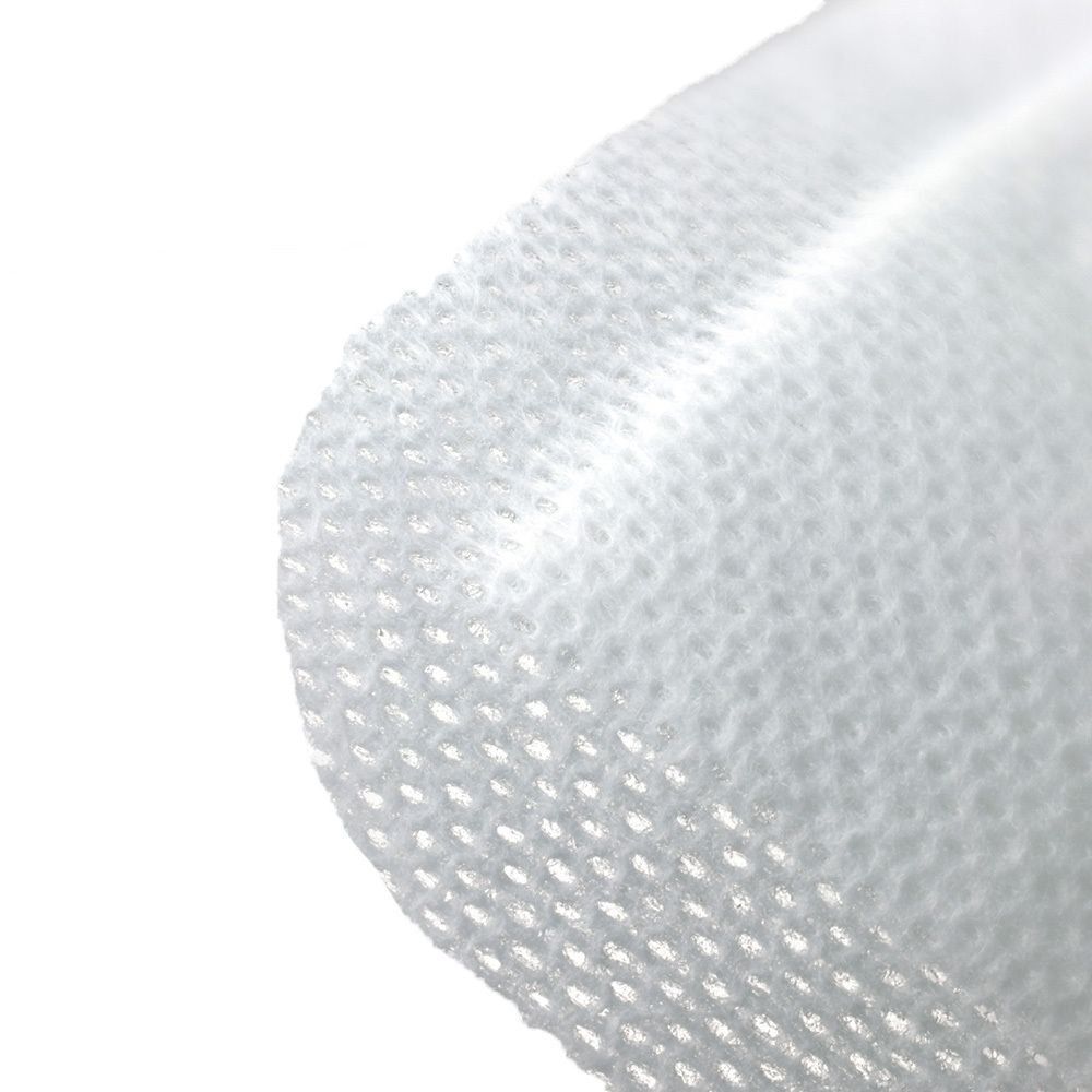 Nahaufnahme eines weißen, gewebten Verbandsmaterials mit kleinen Löchern. Der Verband ist leicht gewölbt.