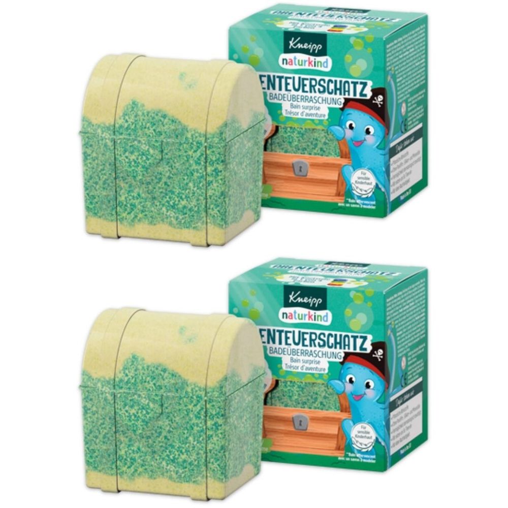 Zwei Schatztruhen-förmige Badezusätze mit grünem und gelbem Farbverlauf. Daneben zwei grüne Kartons mit Produktinformationen und Logo.