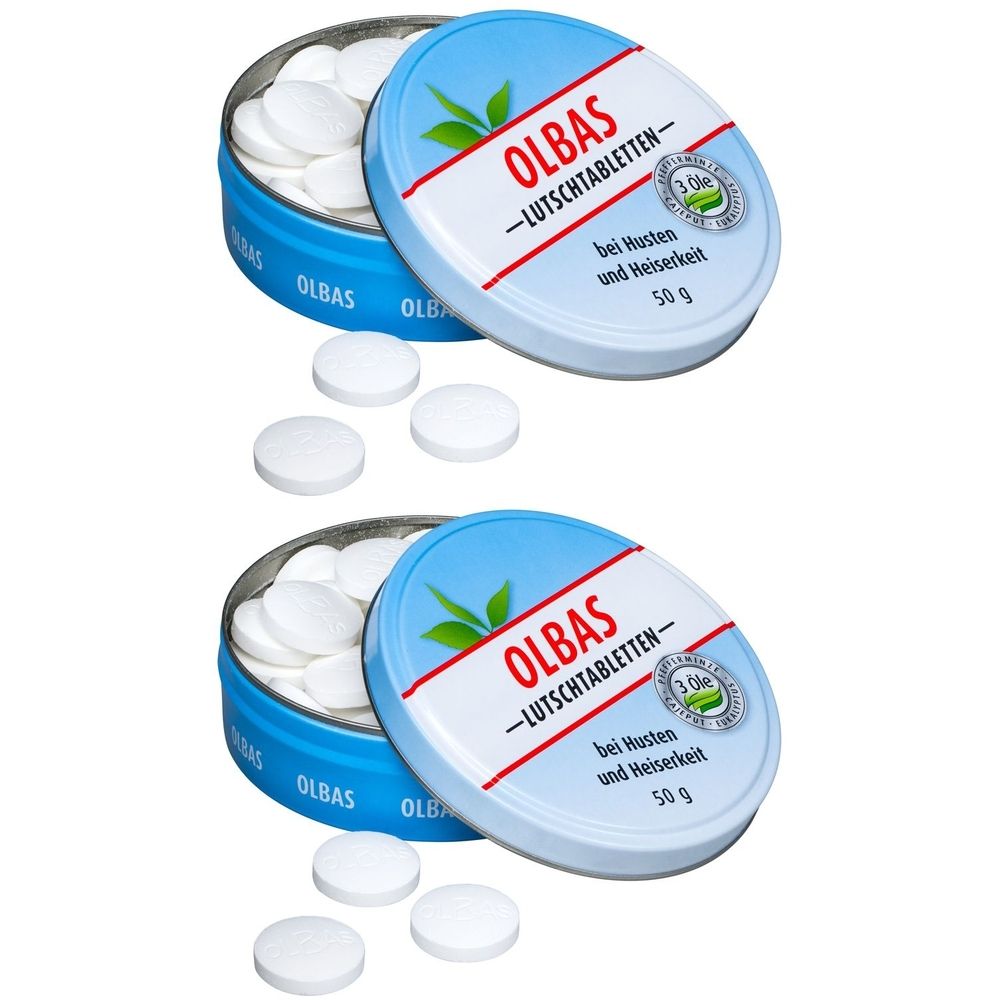 Zwei Dosen mit weißen Lutschtabletten. Blaue Dosen mit weißem Deckel, Aufschrift OLBAS -LUTSCHTABLETTEN-. Tabletten liegen daneben.