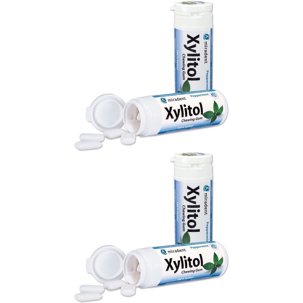 Zwei weiße Kunststoffbehälter mit Kaugummi-Tabletten. Aufschrift "Xylitol Chewing Gum". Ein Behälter geöffnet, Tabletten daneben.