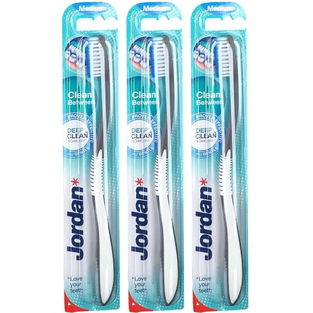 Drei Zahnbürsten in Blisterverpackung. Weiße Griffe, graue Akzente, blaue Borsten. Marke Jordan. Aufschrift: Clean Between, Deep Clean.