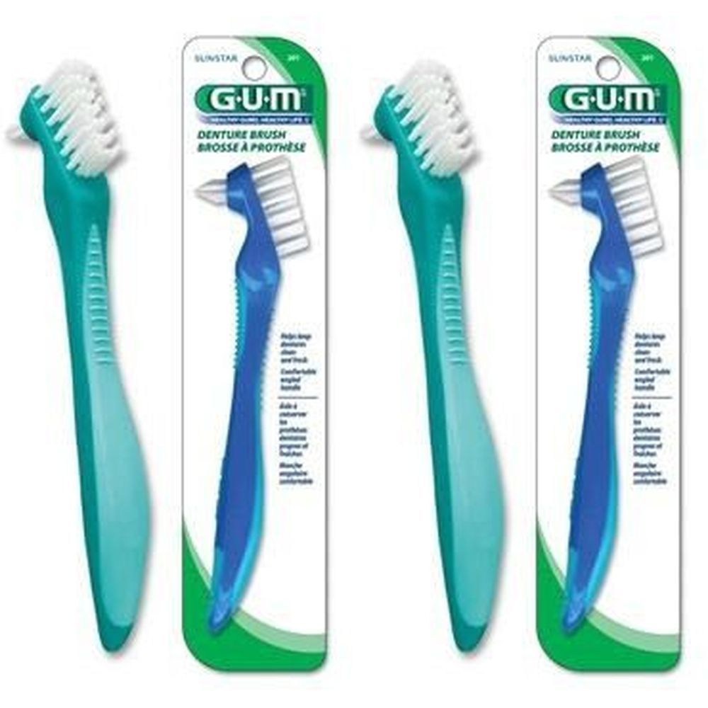 Zwei Zahnbürsten für Prothesen. Grüne und blaue Griffe, weiße Borsten. Verpackt in Blisterverpackung mit Produktnamen.