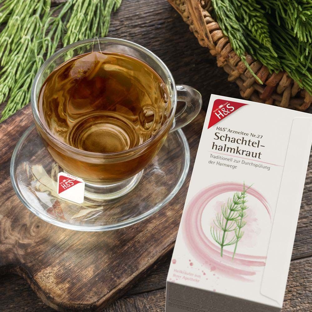 Eine Tasse Tee mit Teebeutel und Packung H&S Schachtelhalmkraut Nr. 27. Auf Holzuntergrund.