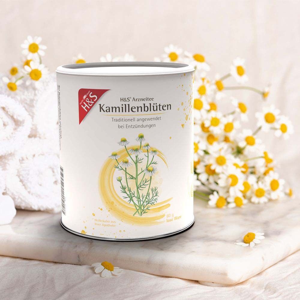Dose H&S Kamillenblüten Tee. Weiße Dose mit Etikett. Roter H&S-Schriftzug. Kamillenblüten-Illustration. Auf Marmor.