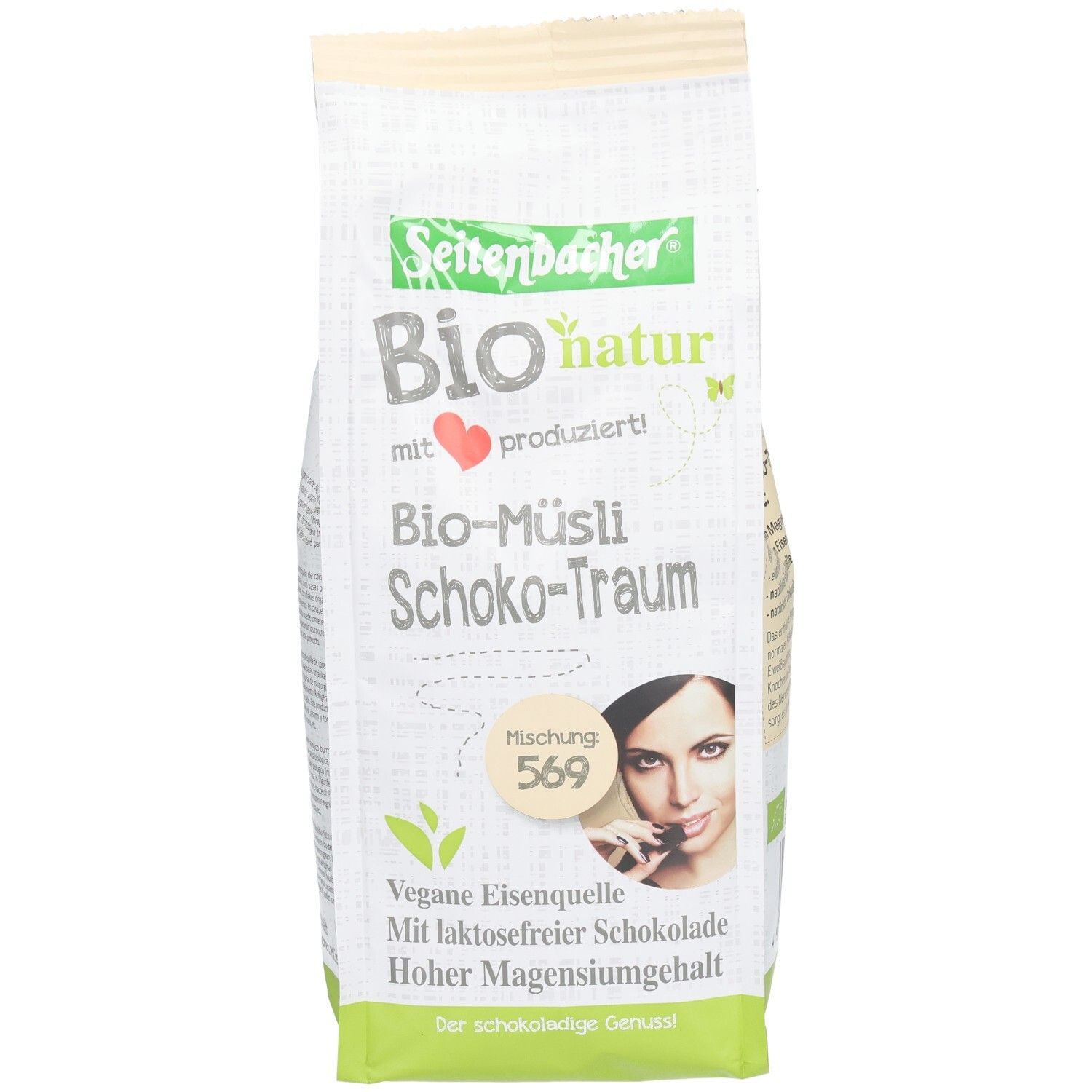 Verpackung von Seitenbacher Bio-Müsli Schoko-Traum. Aufdrucke: Bio-natur, vegane Eisenquelle, laktosefreie Schokolade, hoher Magnesiumgehalt. Frau mit Schokoriegel.