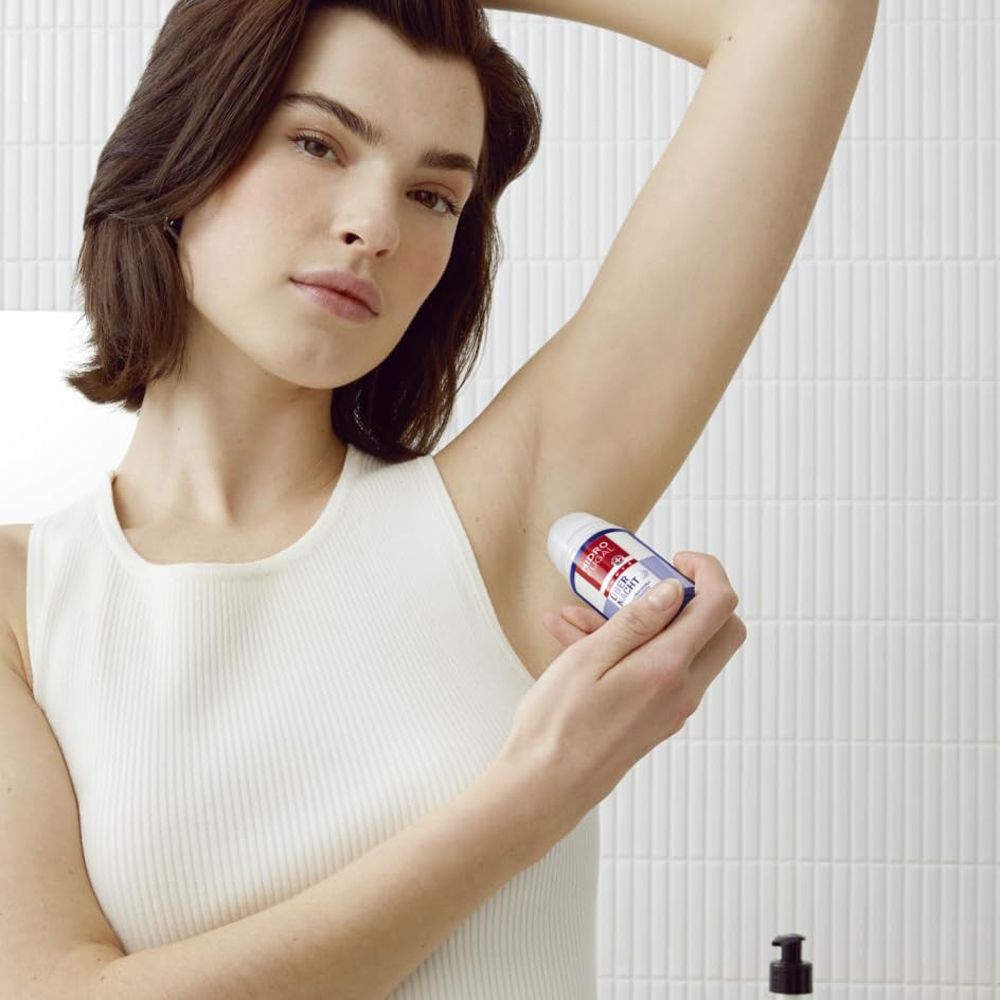 Frau trägt Hidrofugal Forte Über Nacht Roll-on unter dem Arm auf.