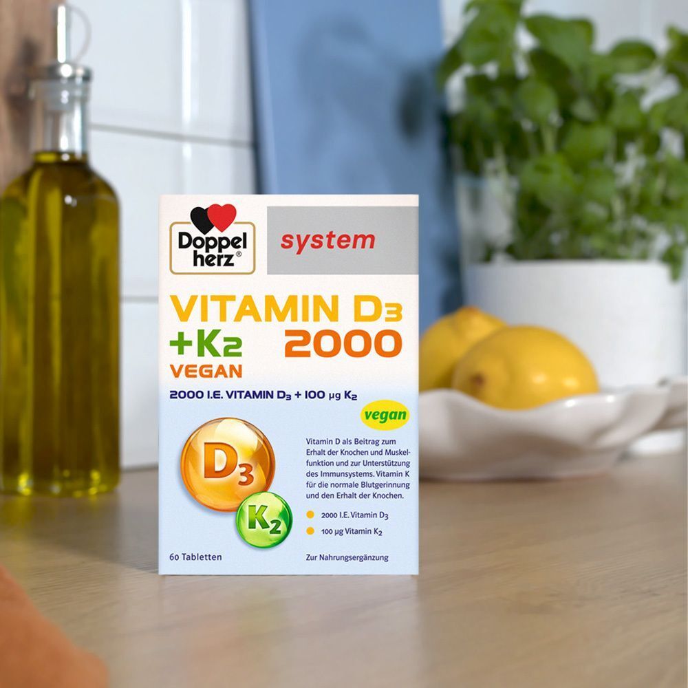 DOPPELHERZ Vitamin D3 + K2 2000 Tabletten-Packung. Weiße Verpackung mit Logo, Produktnamen und vegan-Hinweis. Auf einer Theke.