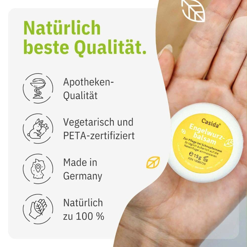 Hand hält einen weißen Tiegel mit gelbem Deckel. Auf dem Deckel steht "Casida Engelwurz-balsam".