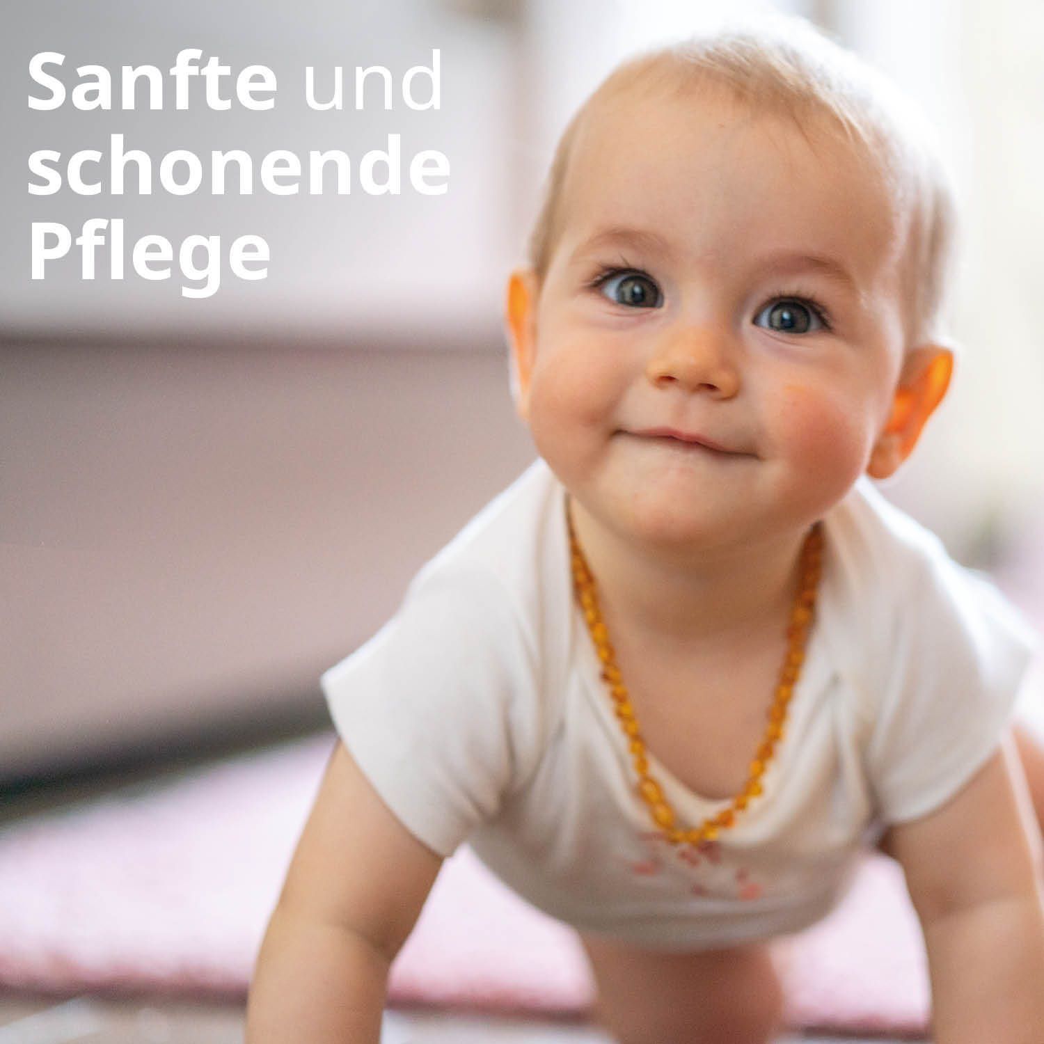 Ein Baby krabbelt auf einem Teppich. Text: Sanfte und schonende Pflege. Das Baby trägt eine Bernsteinkette.