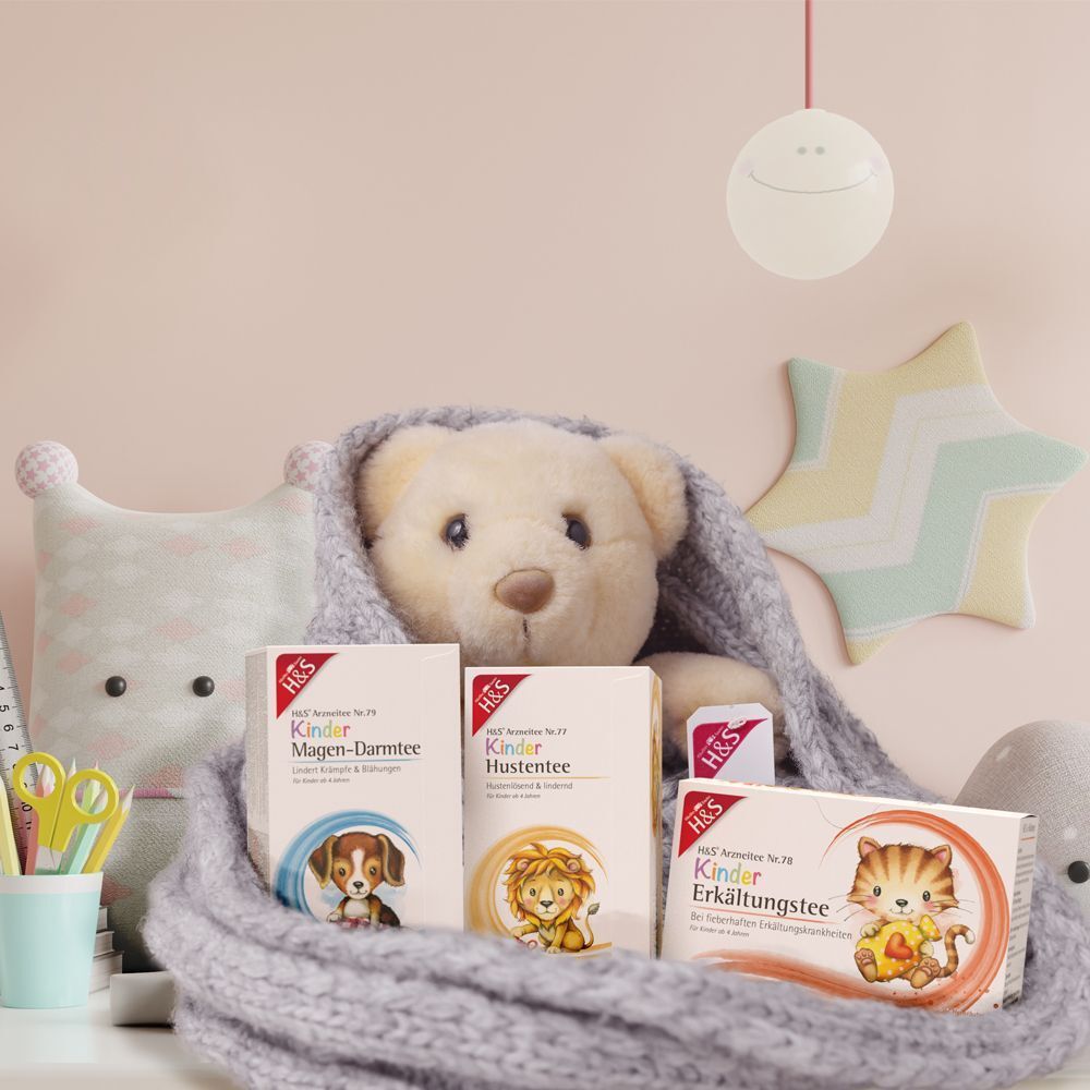 H&S Kinder Erkältungstee Packung neben Teddybär und Spielzeug.