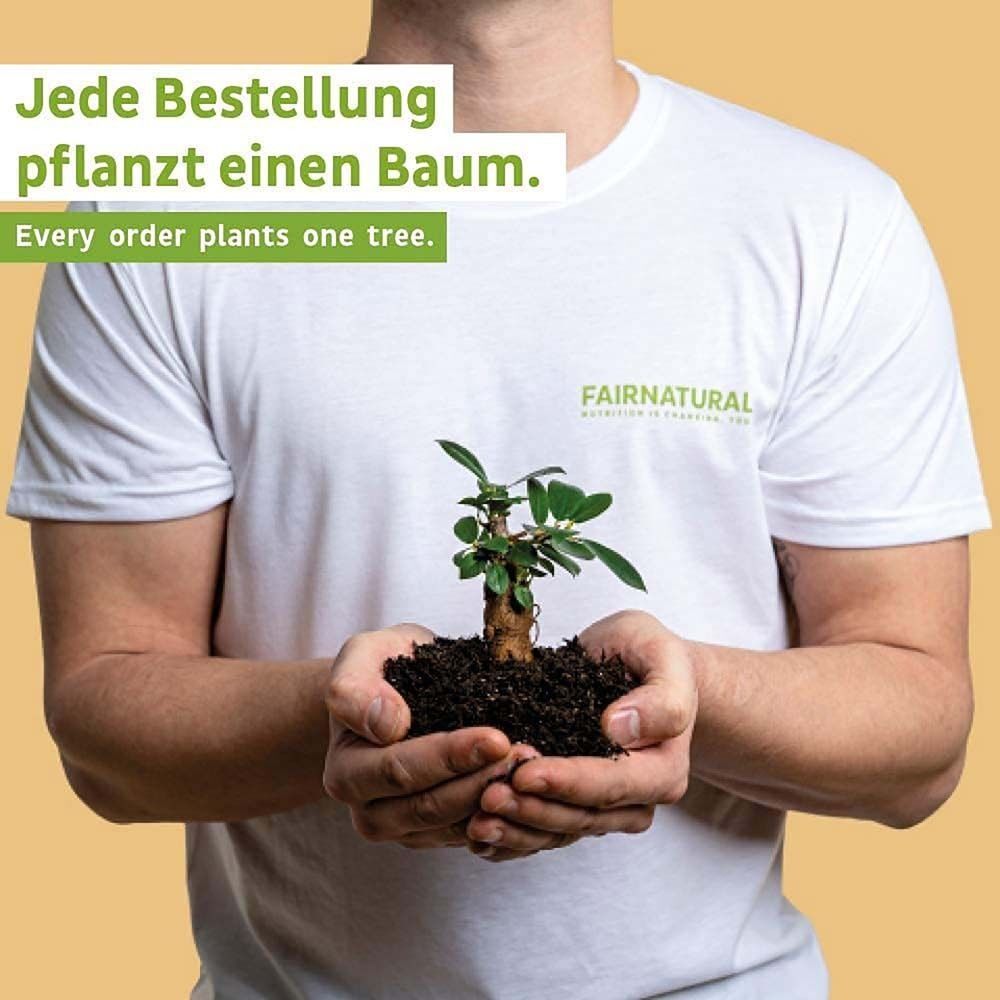 Person hält Setzling in den Händen. Trägt weißes T-Shirt. Hintergrund: Erde.
