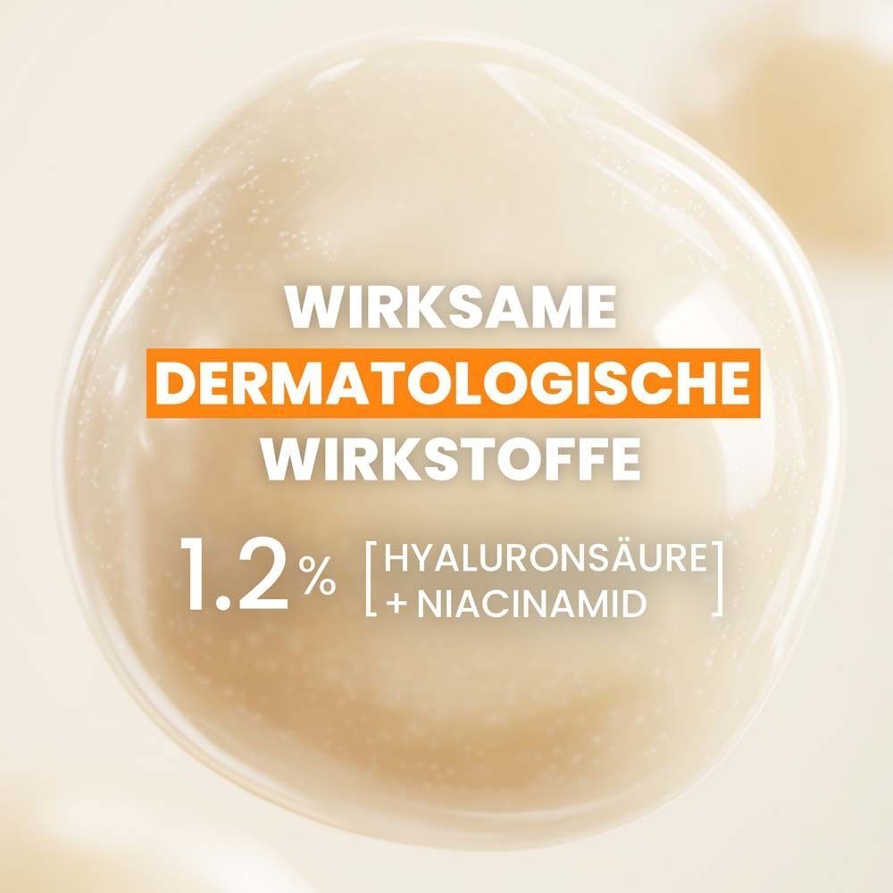 Nahaufnahme einer Serum-Tröpfchen. Text: 1.2% Hyaluronsäure + Niacinamid. Hintergrund: hell.